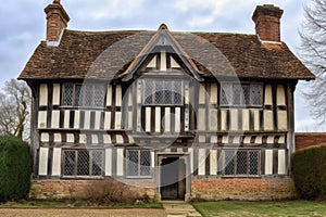 tudor house, with wooden exterior and weathered shingles, viewed from the front