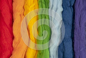 Tufts of wool of different colors parallel to each other form a rainbow. Conceptual photo