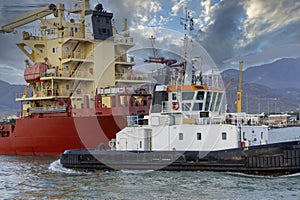 tug boat enter with a ship in marina di carrara harbour