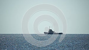 Tug boat in open calm sea, heading back to port at sunset, helps large container ships maneuver. Aerial view, maritime