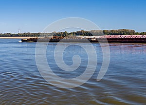 Tug boat pusher behind freight barges loaded with scrap metal on Mississippi River