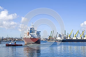 Tug boat towing container ship in harbor