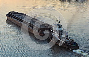 The tug boat towing an empty barge. Evening view. Kyiv, Ukraine