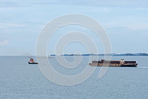 Tug boat tows bulk cargo lighter barge along Singapore strait