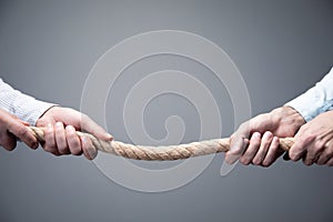 Tug war, two businessman pulling a rope in opposite directions