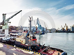 Tugboat assist on a pier in the harbor, cargo sea port over the sea, Floating cargo crane, Granary elevators, harbor, boats and