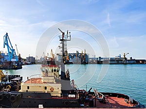 Tugboat assist on a pier in the harbor, cargo sea port over the sea, Floating cargo crane, Granary elevators, harbor, boats and