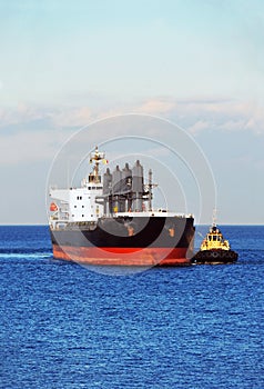 Tugboat assisting bulk cargo ship