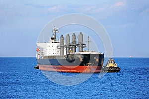 Tugboat assisting bulk cargo ship