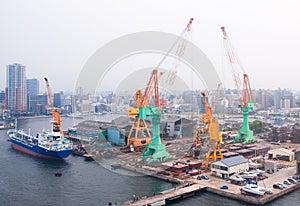 Tugboat assisting bulk cargo ship to harbor quayside