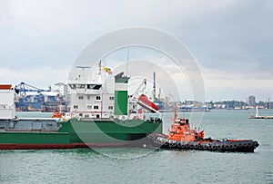 Tugboat assisting refrigerated cargo carrier