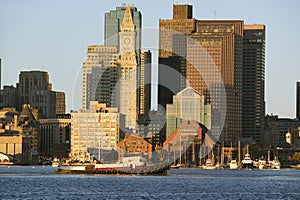 Tugboat with Boston Harbor and the Boston skyline at sunrise as seen from South Boston, Massachusetts, New England