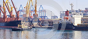 Tugboat at the bow of cargo ship , assisting the vessel to maneuver in Port