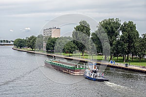 Tugboat with cargo at Dutch Amsterdam-Rijn canal near city Utrecht