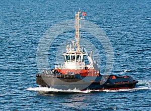 A tugboat with a Danish flag navigates on the sea