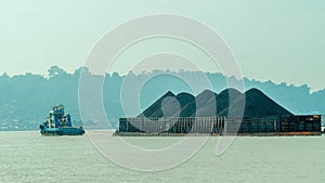 Tugboat drag barge full of coal crossing Mahakam River, Samarinda, in the morning.