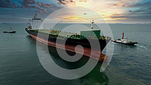tugboat dragging cargo ship leaving shipyard after repairs in green sea and twilight sky and airplane background, front view wide