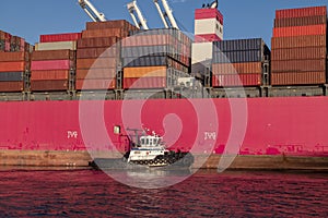 Tugboat guiding a container ship during the late afternoon