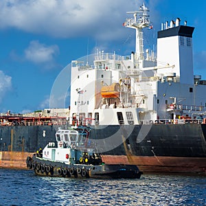 Tugboat guiding a huge cargo ship