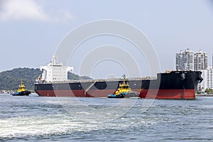 Tugboat maneuvers a ship at port fo Santos, Brazil