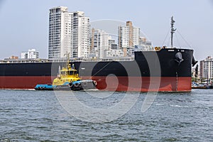 Tugboat maneuvers a ship at port fo Santos, Brazil