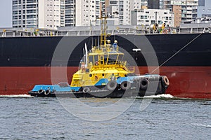 Tugboat maneuvers a ship at port fo Santos, Brazil