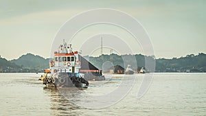 Tugboat pull heavy loaded barge of coal