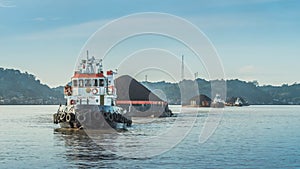 Tugboat pull heavy loaded barge of coal