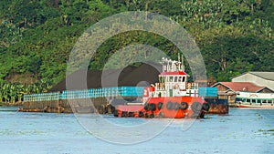 Tugboat pulling barge full of black coal in Mahakam river, Borneo, indonesia