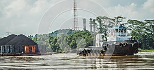 Tugboat pull heavy loaded barge of coal