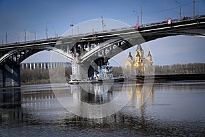 A tugboat pushes a barge under the span of a large bridge.