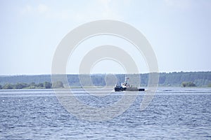 Tugboat pushes sand debris along the river