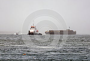 Tugboat towing a barge on rough sea in the fog