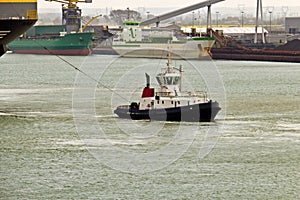 Tugboat towing ship in harbor