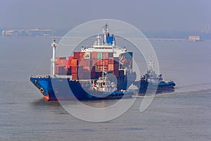 Tugboats assist container ship.