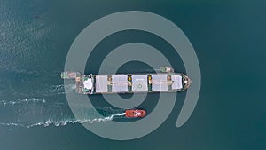 Tugboats pull a big ship with a helipad by sea. Look at the scrunch. Aerial drone shot boat speed sailing in blue sea