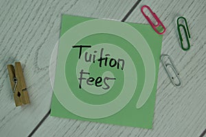 Tuition Fees write on sticky notes isolated on Wooden Table