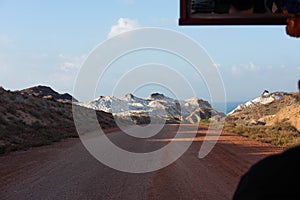 Tuk tuk ride in the beautiful island of Hormuz in Iran. Riding rickshaw around dirt roads with incredible white mountains that