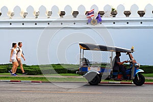 Tuk tuk and tourist walking near grand palace wall thailand tuk tuk is popular transportation