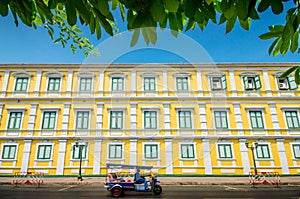 Tuktuk taxi in front of yellow building