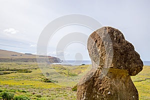 Tukuturi, a moai, possibly  one of the last moai ever made, with on the background Ahu Tongariki and the coast of Easter Island