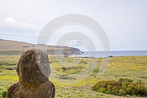 Tukuturi, a moai, possibly  one of the last moai ever made, with on the background Ahu Tongariki and the coast of Easter Island