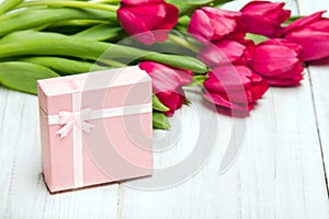 Tulip bouquet and small gift box on white wooden background,