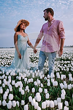 Tulip flower field during sunset dusk in the Netherlands Noordoostpolder Europe, happy young couple men and woman with