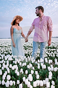 Tulip flower field during sunset dusk in the Netherlands Noordoostpolder Europe, happy young couple men and woman with