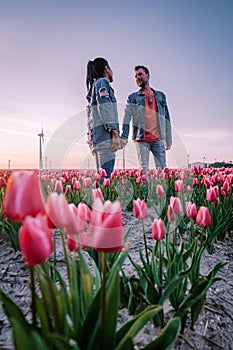 Tulip flower field during sunset dusk in the Netherlands Noordoostpolder Europe, happy young couple men and woman with