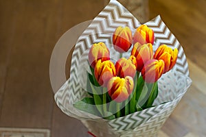 Tulip flowers covered with white paper standing on wooden floor. Best gift for holiday. Concept of love, tenderness, copy space,