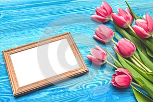 Tulip flowers and empty photo frame on wooden background with copy space. Woman day concept. Romantic background.