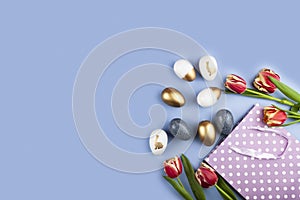 Tulip flowers, gift bag and golden easter eggs on blue background