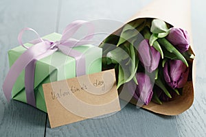 Tulip flowers with green gift box and paper card on blue wood table for valentines day